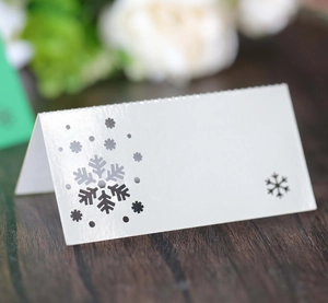 Close-up of white snowflake laser-cut place cards on a dark wooden background
