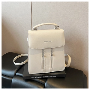 Macro shot of cream white backpack with fashion typography and metallic chain details
