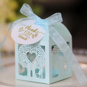 Close-up of light blue laser-cut wedding candy box with heart tree design and ribbon