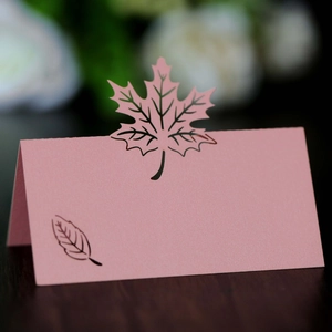 Detailed macro shot of a laser-cut pink paper place card with an elegant maple leaf design