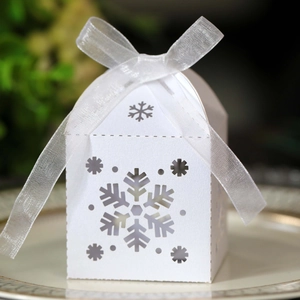 Detalle macro de caja de dulces blanca con copo de nieve hueco y lazo sobre bandeja