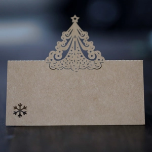 Detail of laser-cut Christmas tree and snowflake design on kraft paper place cards