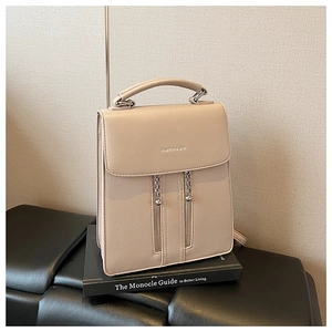 Detail of beige faux leather backpack with parallel zippers and metal chain decor