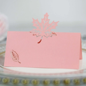 Macro detail of pink pearlescent maple leaf laser-cut place card on a gold-rimmed plate