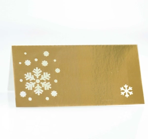 Macro shot of gold metallic place card featuring laser-cut snowflake patterns for Christmas