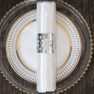 Close-up of a silver snowflake napkin ring on a white satin cloth with festive decor