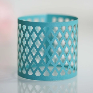 Macro detail of sky blue laser-cut cupcake wrapper with geometric diamond grid pattern