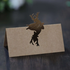 Macro shot of reindeer hollow laser-cut kraft paper place cards on a dark wood table