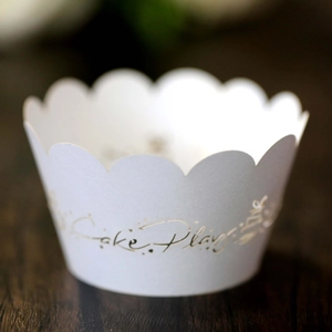 Macro detail of laser-cut white paper cupcake wrapper with hollow floral lace pattern