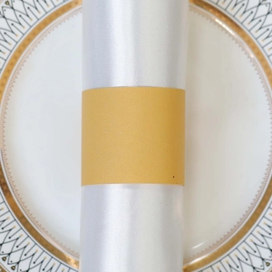 Close-up of golden sparkle paper napkin ring on white satin napkin with gold rimmed plate