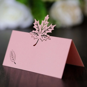 Macro view of pink laser-cut maple leaf place card with a pearlescent finish on wood