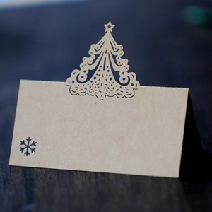 Macro shot of laser-cut Christmas tree craft paper place card on wooden table
