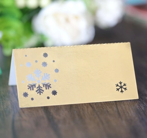 Detail of laser-cut gold snowflake place card on wood surface for Christmas table decor