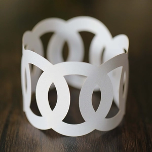 Macro detail of white laser-cut paper napkin ring with elegant interlocking circles