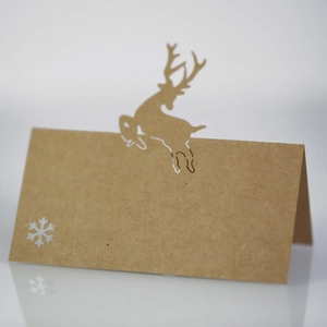 Detail of brown kraft paper place card with laser-cut reindeer and snowflake pattern