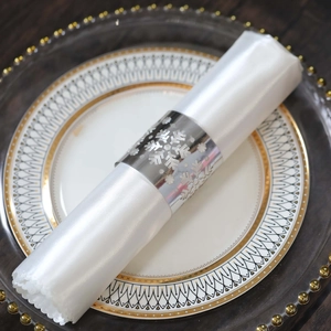 Detail showing shiny silver snowflake napkin ring on white silk cloth for Christmas dinner