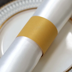 Macro shot of elegant golden pearlescent napkin ring on white satin fabric