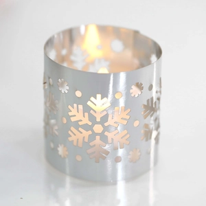 Close-up of a silver snowflake cutout candle holder with warm tea light glow inside