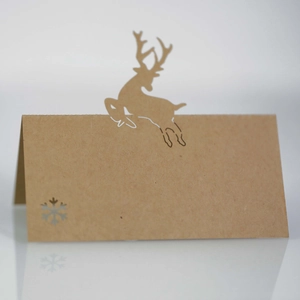 Detail of laser-cut reindeer and snowflake kraft paper place card standing on a surface