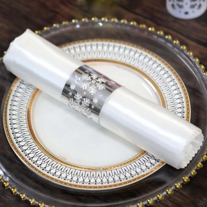 Detailed view of silver snowflake napkin ring on a white silk cloth for table decor