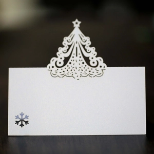 Macro shot of pearl white laser-cut Christmas tree place card on a wooden table