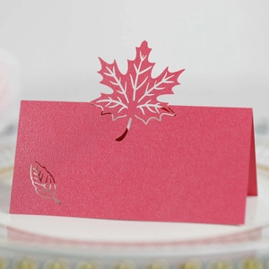 Macro view of laser-cut red pearlescent place card with maple leaf cutout detail