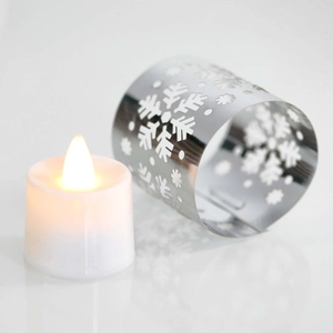 Close-up of LED candle with silver snowflake cutout metal sleeve for festive decor