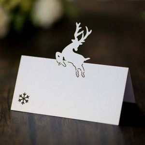 Macro shot of white kraft place card with laser-cut reindeer and snowflake for wedding