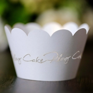 Vista macro de moldes para cupcakes blancos con borde ondulado y letras doradas elegantes