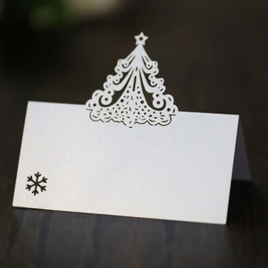 Close-up of laser-cut white Christmas tree place card with snowflake on a wooden surface