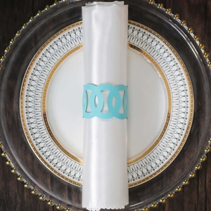 Sky blue hollow geometric napkin ring on a white silk napkin and elegant gold rimmed plate