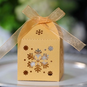 Detalle de copos de nieve cortados con láser en una caja de regalo dorada festiva