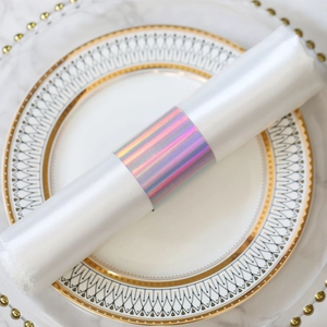 Macro shot of iridescent holographic napkin ring with white satin cloth on marble table