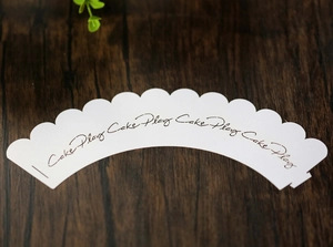 Detalle de envoltorio blanco para cupcake con borde festoneado e impresión de Cake Play
