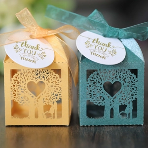 Detail of laser-cut heart tree candy boxes with silk ribbons and golden gift tags