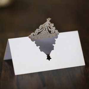 Macro detail of white laser-cut Christmas tree place card with elegant hollow design