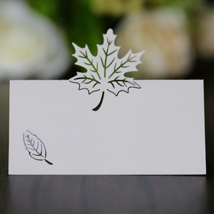 Macro shot of white laser-cut maple leaf place card with pearlescent finish on wood