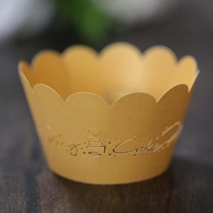 Macro detail of laser-cut gold cupcake wrapper with scalloped edge and cake pattern