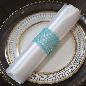 Detail view of sky blue laser-cut lattice napkin ring on a white silk cloth over fine china
