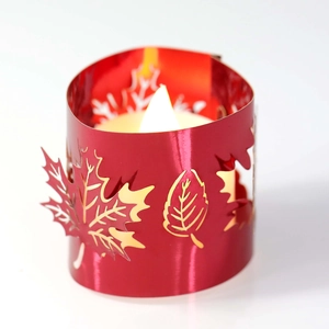 Close-up of red hollowed metal candle cover with maple leaf and snowflake patterns