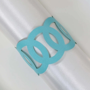 Close-up of laser-cut sky blue triple ring paper napkin holders on white silk