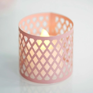 Pink laser-cut paper candle lantern with warm yellow LED light and mesh pattern
