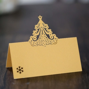 Close-up of laser-cut Christmas tree place card in gold paper for holiday table setting