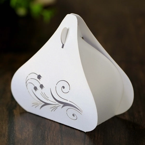 Macro view of white pearlescent wedding favor box with elegant floral vine patterns