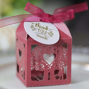 Macro shot of burgundy laser-cut gift box with hollow tree design and thank you tag