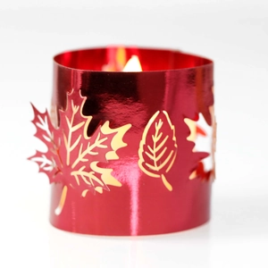 Macro view of red laser-cut metal candle holder with maple leaf hollow patterns