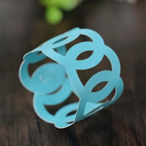 Detail of light blue laser-cut paper napkin rings with interlocking circles on wood