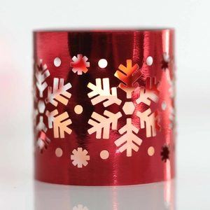Detail of red metallic candle holder sleeve featuring hollow snowflake and dot patterns