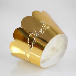 Detail of laser-cut golden crown cake wrappers with elegant white artistic printing
