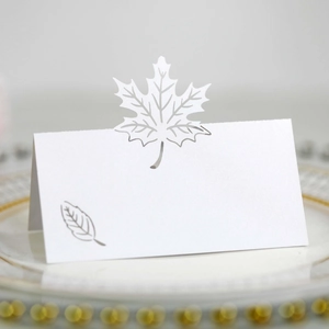 Macro view of white laser-cut maple leaf place card on a gold-rimmed plate